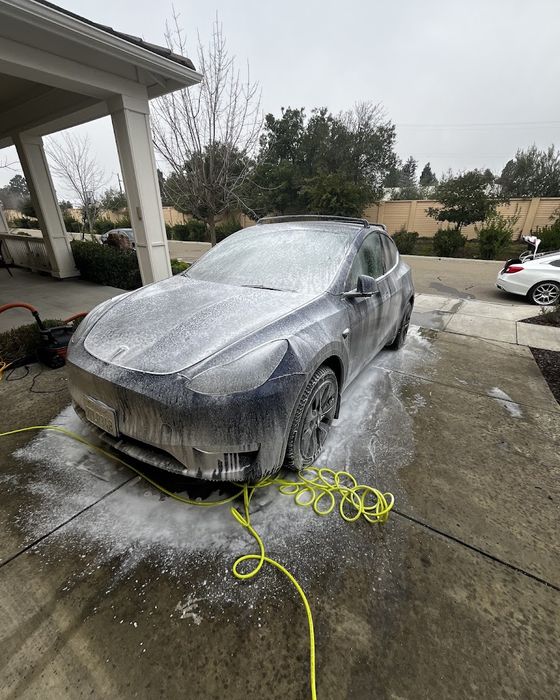 A car covered in snow foam on a driveway during a Gordos Suds mobile detail