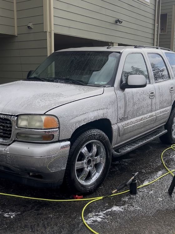 A full-size SUV covered in foam mid-wash at a customer's home