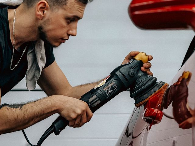 A machine polisher being run along a car panel
